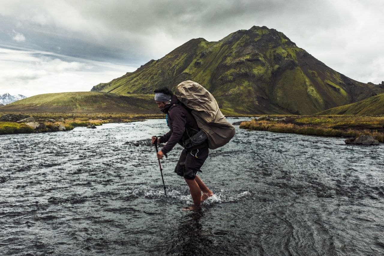 Hud Wahab crossing a river on a backcountry trek